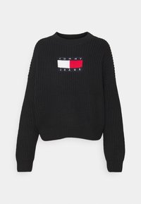 Svart stickad tröja med långa ärmar och en Tommy Jeans-logotyp i röd, vit och marinblå på bröstet.