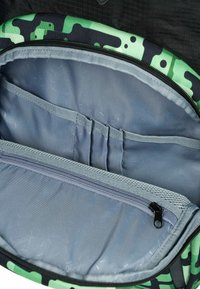 Interno dello zaino a motivo mimetico con fodera grigia, tasca con zip e molteplici scomparti interni per l'organizzazione. Texture morbida.