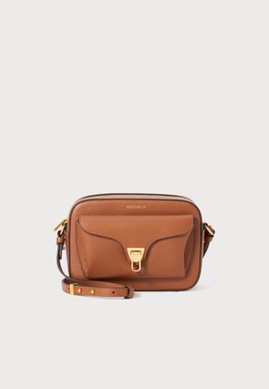 Sac bandoulière en cuir tan avec une finition texturée, comportant une poche à rabat à l'avant et des éléments en métal doré. Sangle réglable incluse.