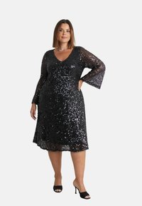 Černé šaty s flitry a hlubokým V výstřihem, s dlouhými rozšířenými rukávy. Šaty mají délku ke kolenům. Nosit s černými vyššími podpatky.