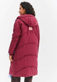 Bordový péřový kabát s kapucí, který má texturovaný prošívaný design, elastické manžety a štítek na zadní straně. Modré detaily se šňůrkou.