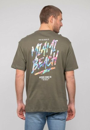 T-shirt en coton vert olive avec un imprimé graphique coloré "MIAMI BEACH" au dos. Manches courtes, coupe décontractée, col rond, texture douce.