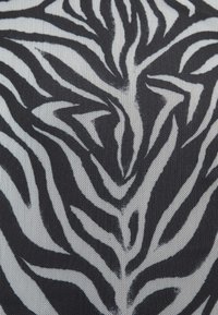 Schwarz-weißes Zebradruckgewebe mit kräftigen, schwankenden Streifen auf einer strukturierten Oberfläche, die ein dynamisches, auffälliges Muster erzeugen.