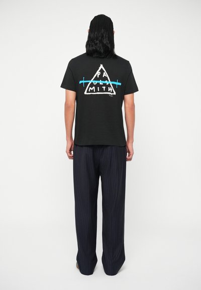 Μαύρη βαμβακερή μπλούζα T-shirt με λευκό και μπλε γραφικό τρίγωνο στην πλάτη, συνδυασμένη με ναυτικές παντελόνες με ρίγες. Πίσω όψη.