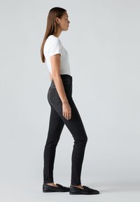 Musta korkeavyötäröinen farkut, slim fit -leikkaus, denim-kangasta, takataskut ja valkoinen ompelu. Yhdistetty valkoiseen t-paitaan ja mustiin ballerinoihin.