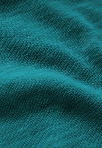 Teal neulottu kangas, jossa on tekstuuripinta, näkyvät tikit ja pehmeä, sileä ilme. Kevyesti laskostettu syvyyden lisäämiseksi.