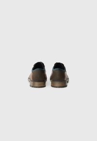 Chaussures en cuir brun avec un accent bleu clair contrastant, profil bas, tige texturée et semelle en caoutchouc striée.