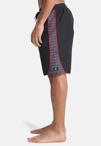 Μαύρα μαγιό σορτς με πλαϊνή λωρίδα σε κόκκινο και γκρι καρό μοτίβο. Λάστιχο στη μέση με ρυθμιζόμενο κορδόνι και λεπτομέρεια λογότυπου.