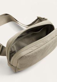 Borsa a tracolla sintetica grigia chiara, con texture, dotata di un comparto con zip, presenta una fodera in rete e una tracolla regolabile.