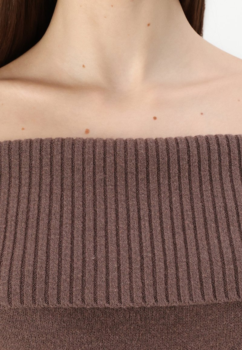 Brauner gerippter Strickpullover mit weitem Ausschnitt und Struktur, aus weichem Stoff, der von der Schulter bis zur Brust reicht.