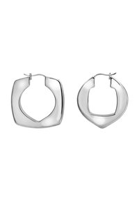 Dvě leštěné stříbrné kruhové náušnice s nepravidelnými čtvercovými tvary a zapínáním na zadní straně na bílém pozadí.