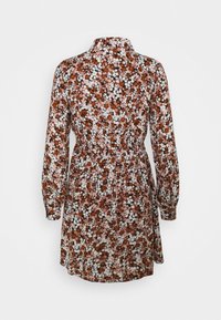 Robe fleurie à manches longues, présentant un motif de fleurs marron, blanc et noir sur un fond rose. Détail de taille cintrée.