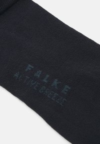Crna čarapa od teksturiranog materijala, sa ispisanim "FALKE" i "ACTIVE BREEZE" u tirkiznoj boji. Udobno prianjanje s jednostavnim dizajnom.
