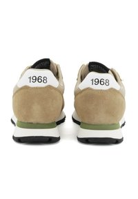 Beige Wildleder-Sneaker mit schwarzen Akzenten, weißen Fersenlaschen mit der Aufschrift '1968' und grünen Details an der Zwischensohle. Gummilaufsohle für Traktion und Langlebigkeit.