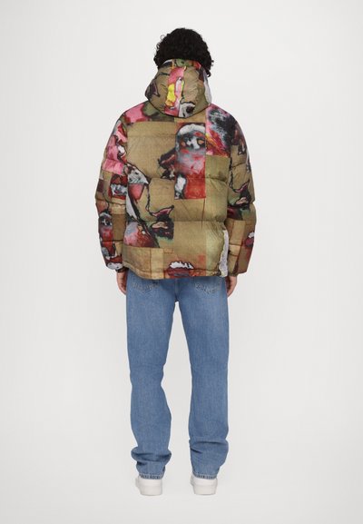 Padded jacket in multicolored fabric featuring graphic patterns. Includes a hood and visible stitching. Paired with light blue jeans.