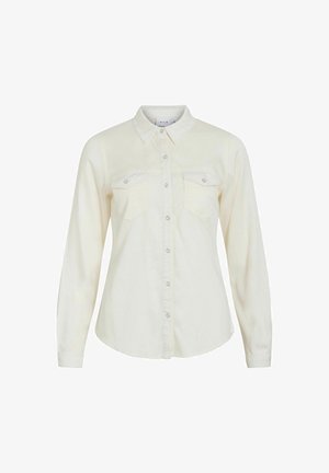 Chemise à manches longues couleur crème en tissu doux, avec un col pointu, deux poches poitrine et une fermeture à boutons avec des boutons en argent.