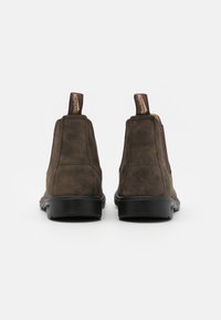 Bottines en cuir marron avec des panneaux élastiques sur les côtés et des languettes de tirage. Semelles en caoutchouc noir, finition lisse et design minimaliste.