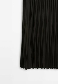 Jupe plissée noire avec des plis verticaux étroits, suspendue sur un fond blanc, montrant la moitié inférieure de la jupe.