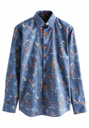 Gros plan sur le col d'une chemise bleue à motifs floraux avec des boutons foncés et un motif floral multicolore détaillé.