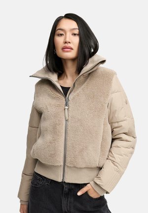 Beige fleece en gewatteerd jack met een hoge kraag, ritssluiting en geribbelde manchetten. Het heeft een zachte, gestructureerde voorkant en gladde mouwen.