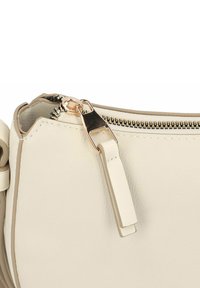 Bolso de mano de cuero color beige claro con cremallera y herrajes en tono dorado. El tirador de la cremallera es plano, y la textura es suave con una forma estructurada.