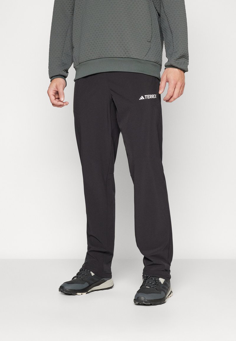 Schwarze Sporthosen mit schmalem Schnitt und elastischem Bund, versehen mit dem weißen TERREX-Logo auf dem linken Oberschenkel. Glatte Fabric-Oberfläche.