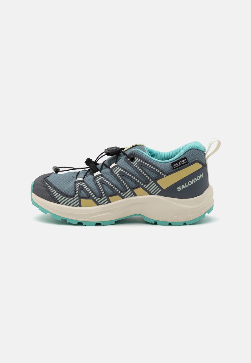 Trail running shoe with a grey upper, turquoise accents, and beige details. Features a textured mesh and a durable sole with traction lugs.