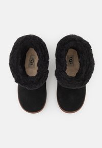 Bottines en suède noir avec un doublure noire moelleuse et des semelles en caoutchouc marron, dotées d'un revers pliable pour un style ajustable.