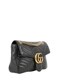 Sac à main en cuir noir matelassé chevron, fermoir avec logo double G doré et bandoulière chaîne dorée sur fond blanc.