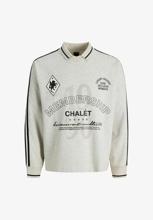 Polo à manches longues gris clair avec des rayures noires sur les manches, détail du col, et texte imprimé incluant "MEMBERSHIP CHALÉT" ainsi qu'un emblème de lion.