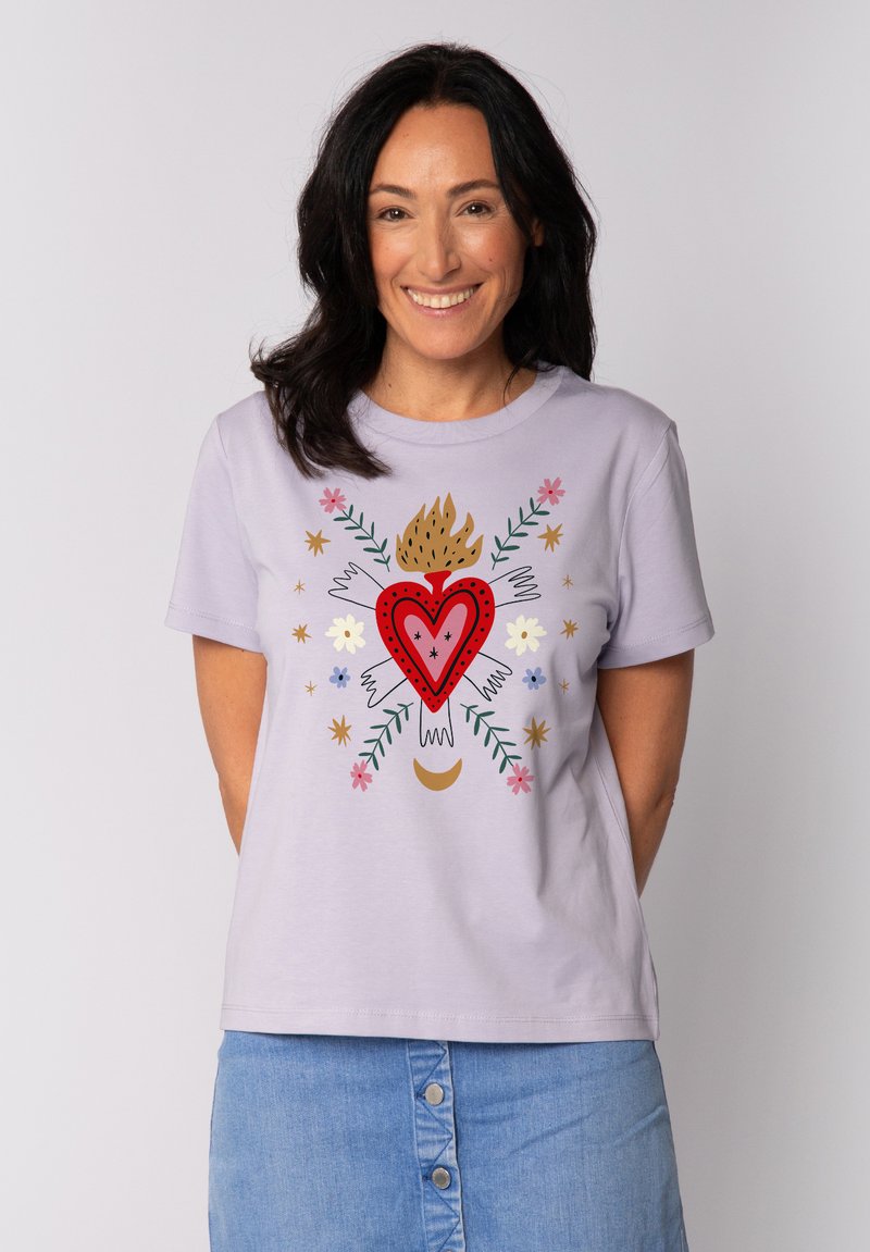 Lichtpaarse t-shirt met een centraal rood hartontwerp met bloemaccenten, handmotieven en een vlam, gecombineerd met een denim rok.