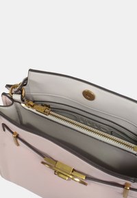 Borsa a tracolla in pelle rosa con hardware dorato, inclusi un gancio e una cerniera. L'interno presenta una fodera di tessuto chiaro e tasche organizzative.