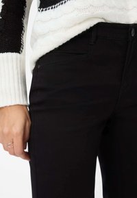Sorte skinny jeans med en glat tekstur, klassisk fem-lomme-design og diskrete syningsdetaljer. Parret med en strikket sweater.