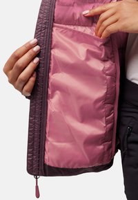 Interno della giacca viola con fodera rosa liscia. Presenta una tasca orizzontale interna, che mostra una texture trapuntata e un dettaglio con zip all'orlo.