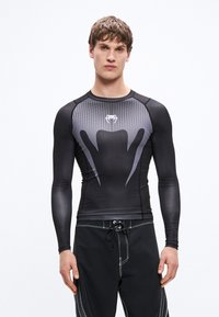 Czarna i szara sportowa koszulka z długim rękawem, z wzorzystą górną częścią, nowoczesnym designem oraz gładkim, elastycznym materiałem.