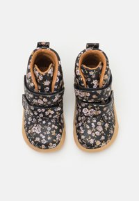 Černé boty s květinovým vzorem vyrobené z materiálu podobného kůži, s polstrovaným interiérem, dvěma nastavitelnými popruhy a gumovými podrážkami pro lepší trakci.