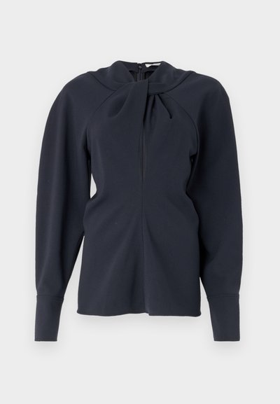 Marineblå langærmet top med foldet krave, lynlåsfortsclosing foran og strukturerede skuldre. Glat stof med minimal tekstur.