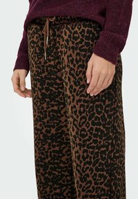 Leopardprint bukser i brun og sort med en elastisk talje og snørelukning samt et struktureret, blødt materiale.