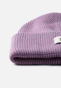 Berretto lavorato a maglia viola ripiegato con texture a coste, dotato di un'etichetta discreta. Il materiale sembra morbido ed elastico.