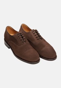 Scarpe oxford in suede marrone con finitura liscia, design a punta chiusa e lacci neri. Presentano una suola in pelle elegante e una forma della punta arrotondata.