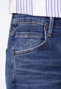 Mörkblå denimjeans med klassisk passform, med framfickor, diskret stickning och en ljus blekning. Etikett placerad nära midjan.