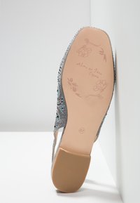 Suola di una scarpa flat grigia con disegni floreali e testo "Alma en Pena España," misura 37, con embellishments scintillanti visibili di lato.
