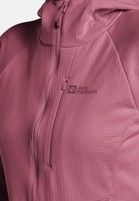 Giacca aderente, leggera e rosa con tessuto testurizzato, zip completa e cappuccio. Presenta il logo Jack Wolfskin in un colore a contrasto.