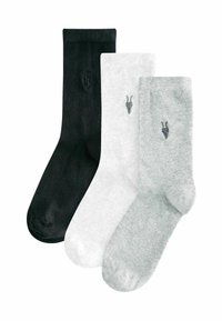 Kolm paari sokke: must, valge ja helehall. Igal paaril on väike tikandiga siga kujutis ja ribaline tekstuur.