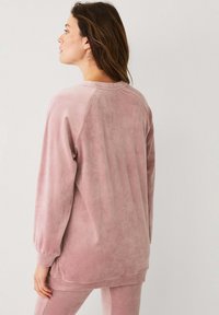 Zachte roze sweatshirt met een relaxte pasvorm, lange mouwen en een gladde textuur. De achterkant benadrukt raglanmouwen en een ronde halslijn.
