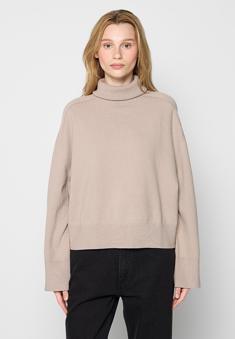 Beige Rollkragenpullover aus weichem, strukturiertem Stoff. Mit überschnittenen Schultern, langen Ärmeln und einem cropped Saum.