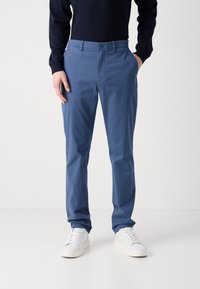 Chinos in cotone azzurro chiaro con una vestibilità slim, tasche anteriori e chiusura con bottone. Abbinati a sneakers bianche per un look casual.