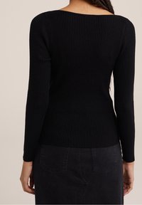 Haut noir à manches longues côtelé avec un col carré, coupe ajustée et tissu texturé, associé à une jupe noire avec des poches arrière.