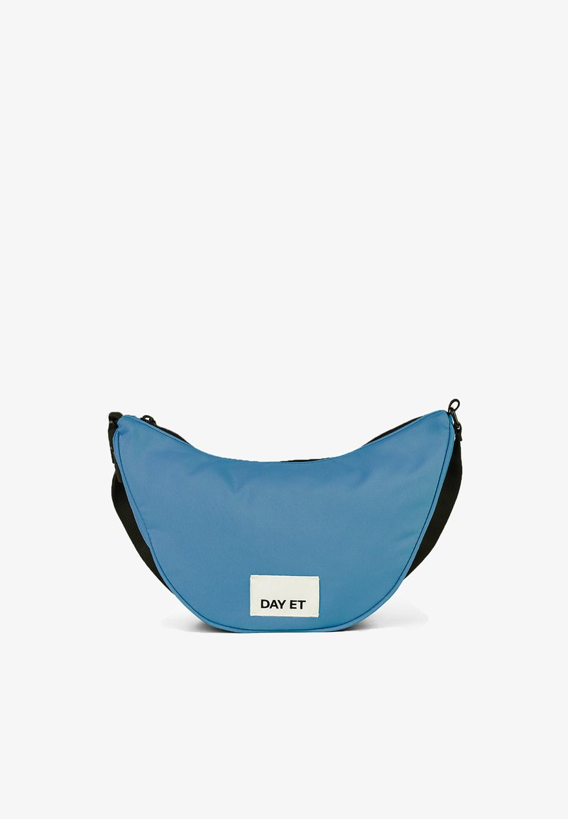 Borsa a tracolla in tessuto blu con forma a mezzaluna, dettagli neri e un'etichetta bianca con la scritta "DAY ET". Texture liscia e chiusura con zip.