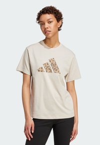 Lichtbeige katoenen t-shirt met een driehoekig logo in luipaardprint op de borst, met korte mouwen en een ontspannen pasvorm.